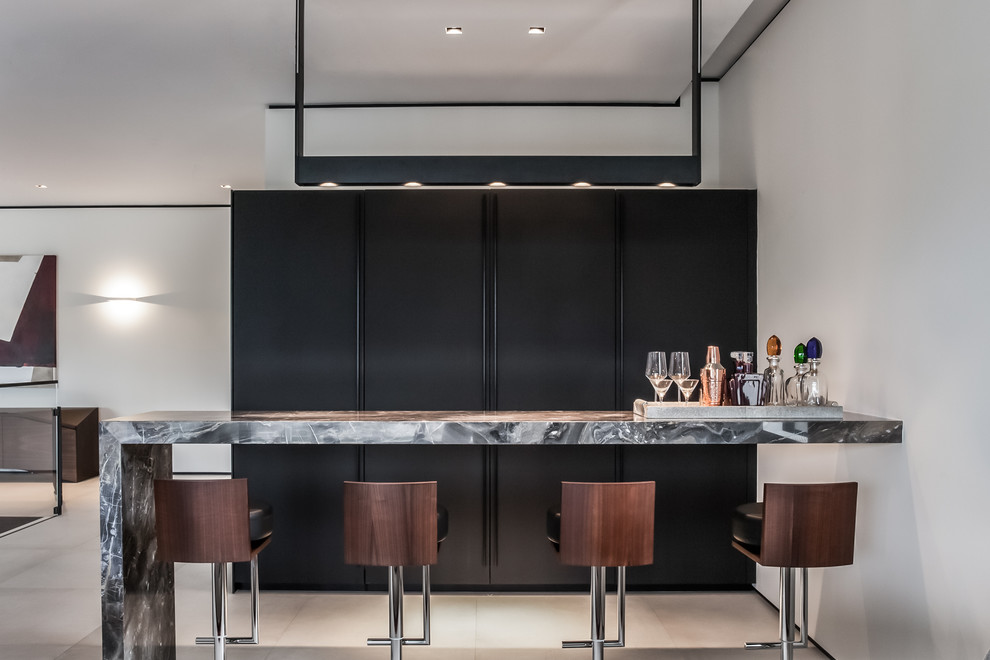 Photo of a large contemporary galley home bar in Miami with flat-panel cabinets, dark wood cabinets, marble benchtops, brown splashback, porcelain floors and grey floor.