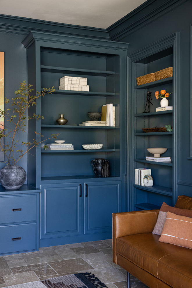 Стильный дизайн: большой домашняя библиотека в стиле неоклассика (современная классика) с синими стенами, полом из травертина и отдельно стоящим рабочим столом - последний тренд
