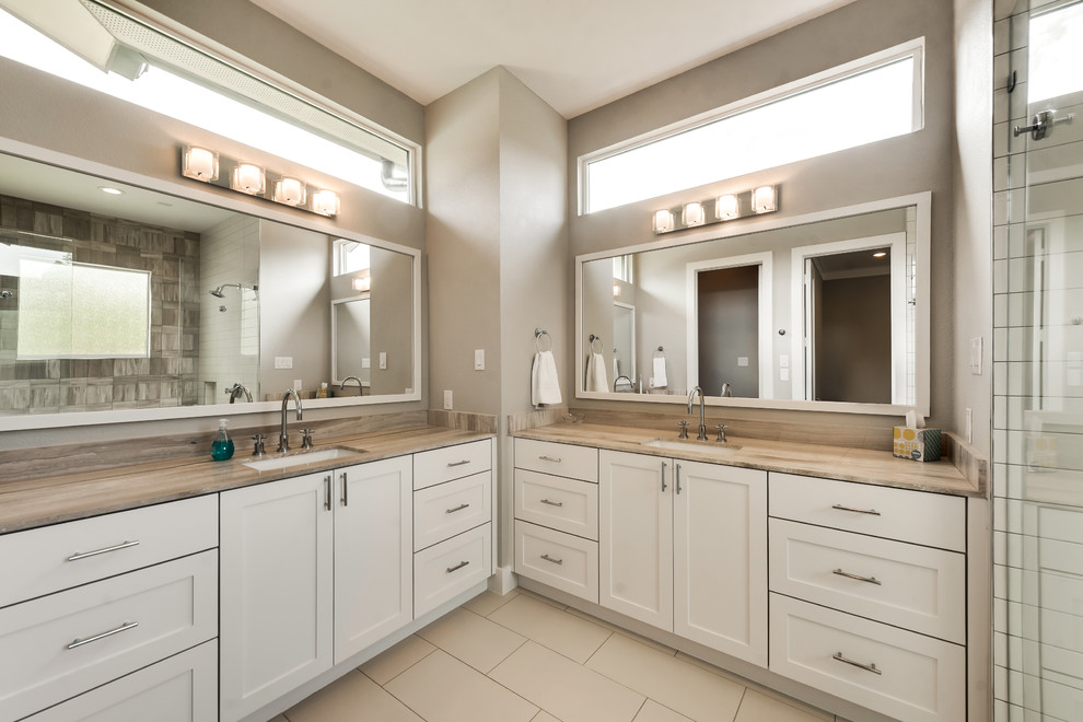 Photo of a country master bathroom in Dallas with shaker cabinets, grey cabinets, beige walls, an undermount sink, beige floor, a double shower, beige tile, limestone benchtops and an open shower.