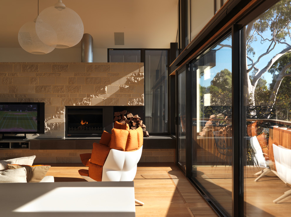 Photo of a large contemporary open concept living room in Melbourne with white walls, medium hardwood floors, a standard fireplace, a brick fireplace surround and a wall-mounted tv.