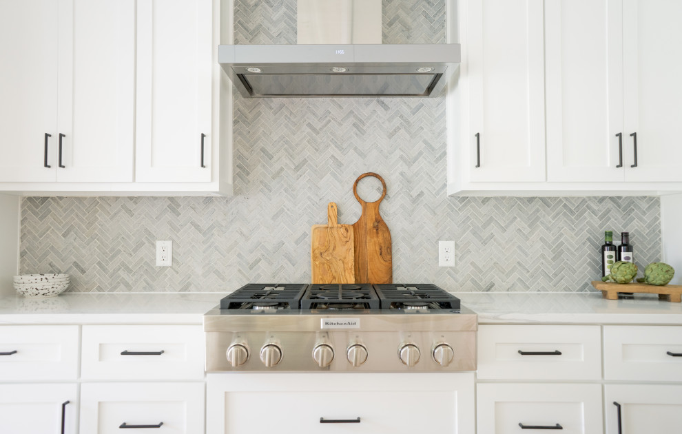 Kitchen - transitional kitchen idea in Austin with a farmhouse sink, shaker cabinets, white cabinets, quartz countertops, gray backsplash and stone tile backsplash