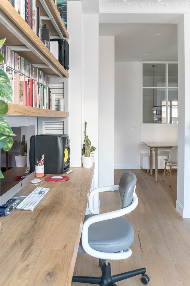 Photo of a small scandinavian home office in Milan with a library, light hardwood floors and a freestanding desk.