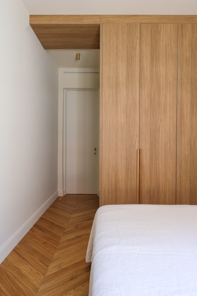 Foto de dormitorio principal y blanco y madera clásico renovado grande sin chimenea con paredes blancas, suelo de madera clara y suelo marrón