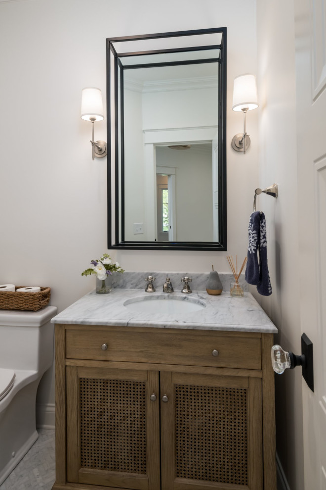 Photo of a mid-sized transitional powder room in Other with furniture-like cabinets, brown cabinets, a one-piece toilet, white walls, mosaic tile floors, an undermount sink, marble benchtops, white floor, white benchtops and a freestanding vanity.