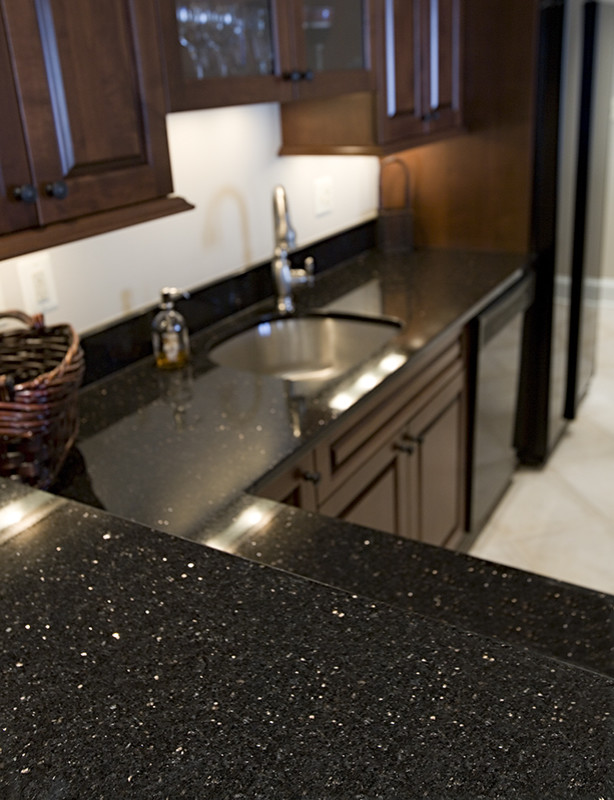 Photo of a l-shaped home bar in DC Metro with an undermount sink, granite benchtops and stone slab splashback.