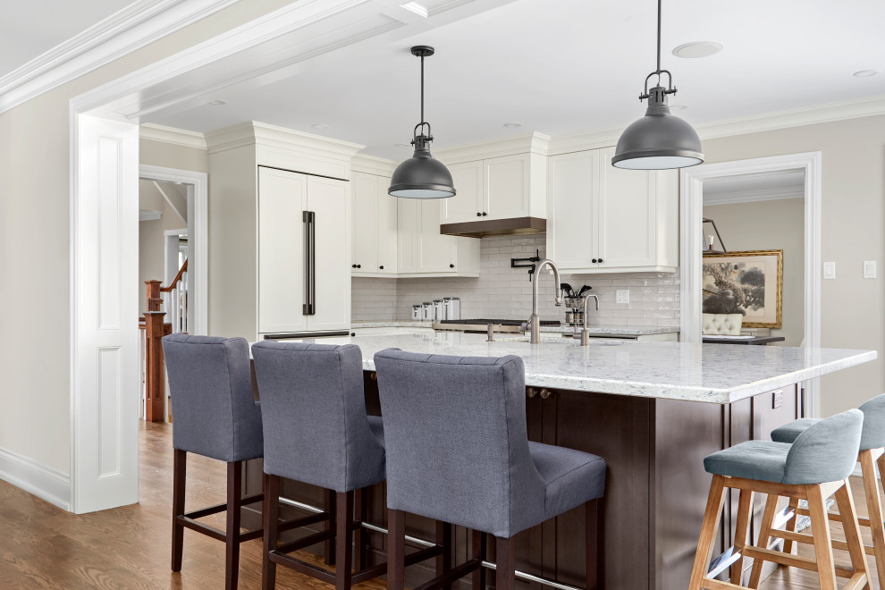 Example of a transitional u-shaped medium tone wood floor and brown floor eat-in kitchen design in Toronto with an undermount sink, shaker cabinets, white cabinets, quartz countertops, white backsplash, subway tile backsplash, paneled appliances, an island and gray countertops