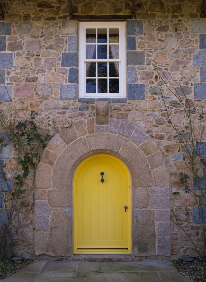This is an example of a country front door in Channel Islands with a single front door and a yellow front door.