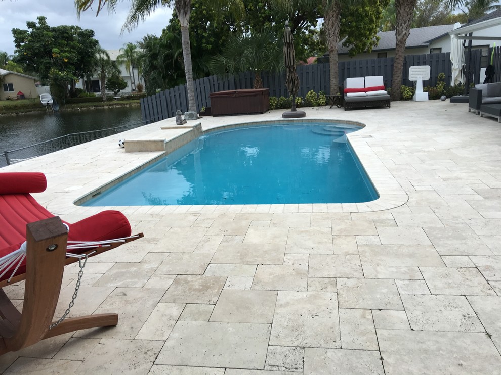 Example of a mid-sized transitional backyard concrete paver and custom-shaped pool design in Miami
