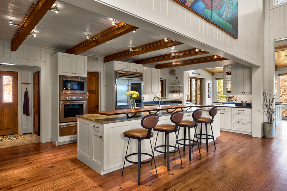Photo of a traditional galley kitchen in Other with stainless steel appliances and white cabinets.