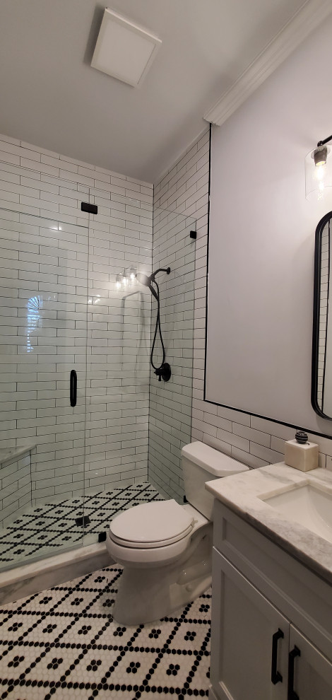 Inspiration for a mid-sized transitional black and white tile and ceramic tile ceramic tile, multicolored floor and single-sink shower bench remodel in Dallas with shaker cabinets, gray cabinets, a two-piece toilet, gray walls, an undermount sink, quartz countertops, a hinged shower door, gray countertops and a built-in vanity