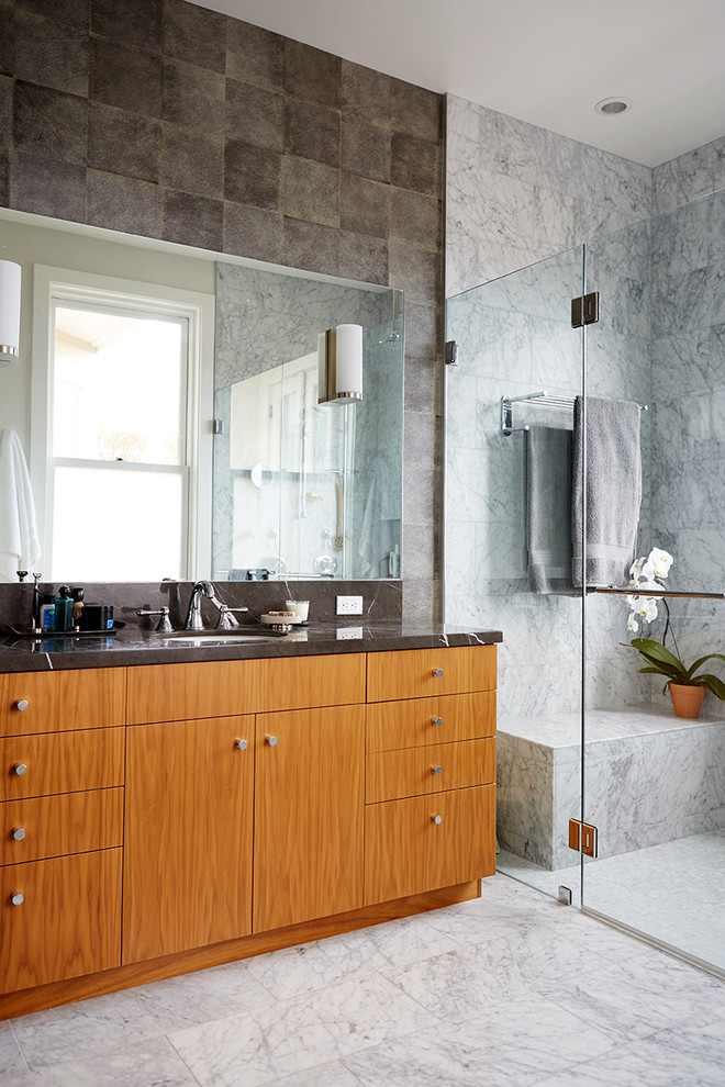 This is an example of a transitional bathroom in Boston with gray tile, grey walls, marble floors, an undermount sink, flat-panel cabinets, medium wood cabinets, an alcove shower and stone tile.