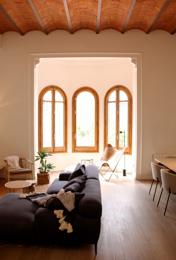 Ejemplo de salón abierto y beige y blanco contemporáneo de tamaño medio con paredes blancas, suelo de madera clara, pared multimedia, suelo beige y vigas vistas