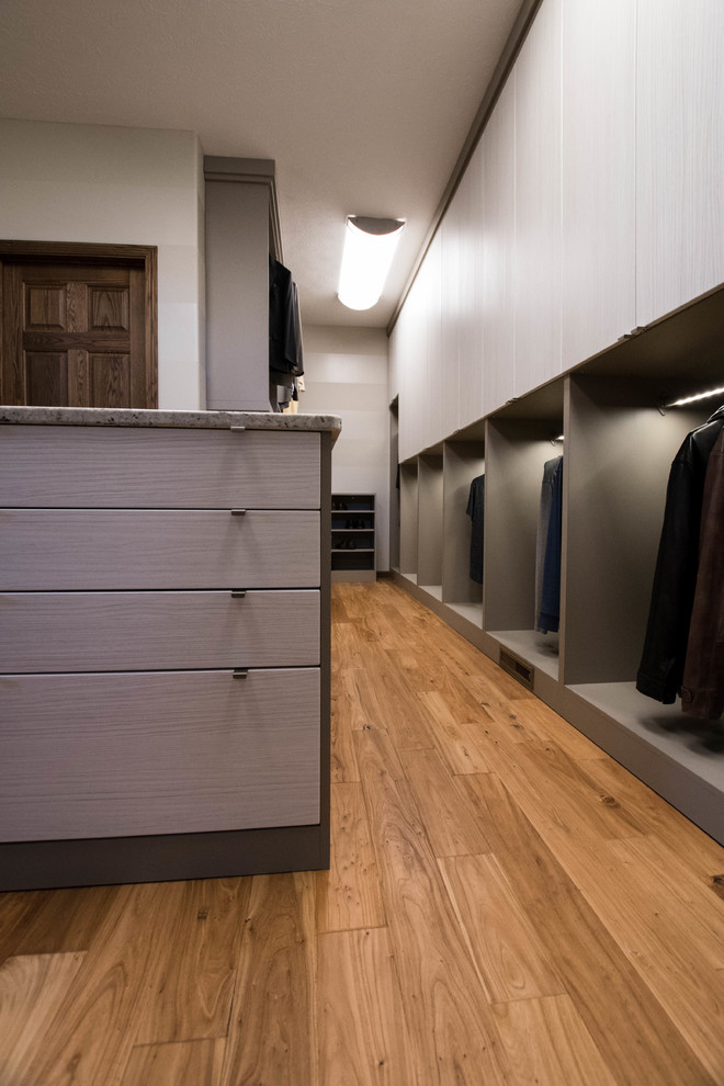 This is an example of a large contemporary gender-neutral walk-in wardrobe in Other with flat-panel cabinets and medium hardwood floors.