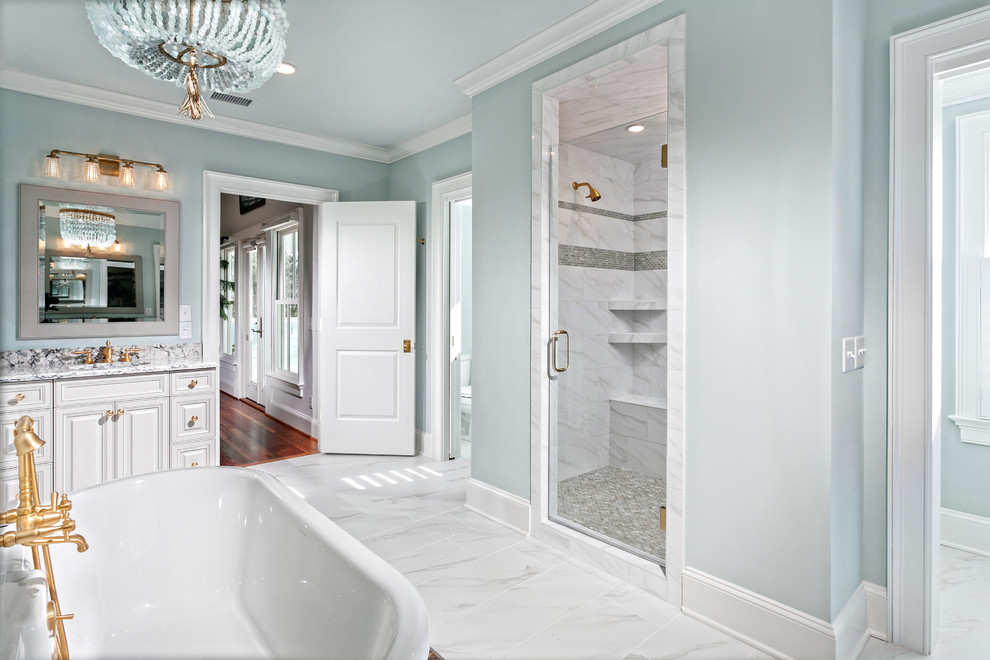 Large beach style master bathroom in Charleston with raised-panel cabinets, a claw-foot tub, an open shower, white tile, marble, marble benchtops, a hinged shower door, grey cabinets, blue walls, marble floors, an undermount sink and white floor.