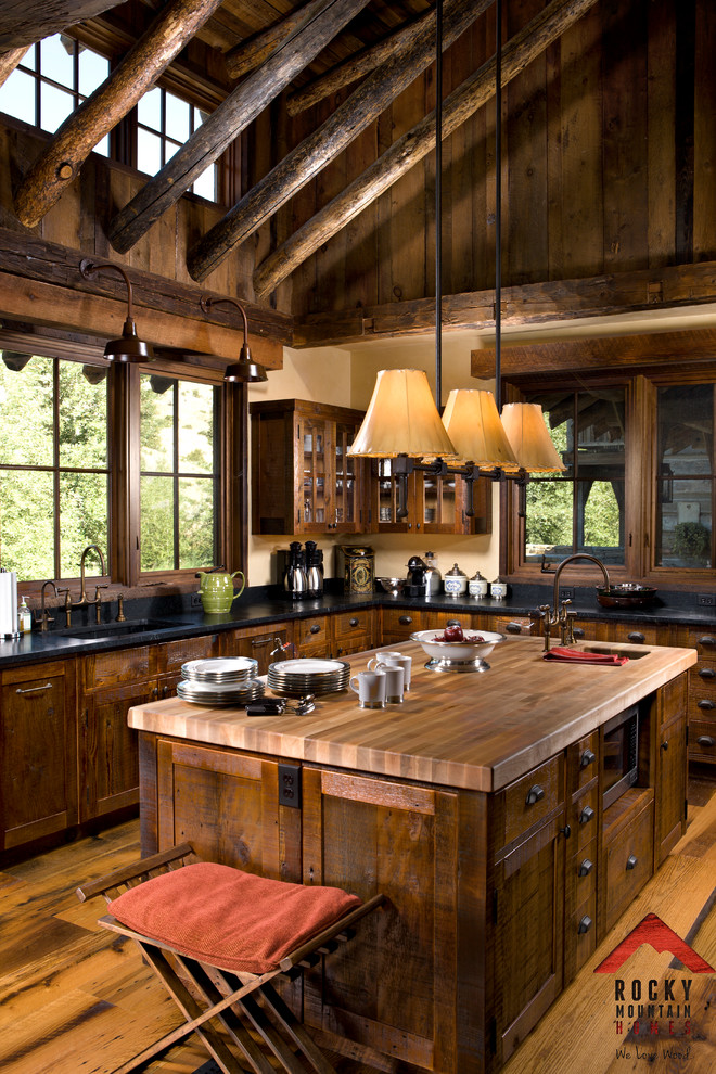 Mid-sized mountain style l-shaped light wood floor eat-in kitchen photo with a farmhouse sink, recessed-panel cabinets, dark wood cabinets, granite countertops, blue backsplash, paneled appliances and an island