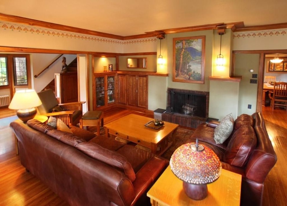 Photo of a large enclosed living room in Minneapolis with green walls, medium hardwood floors, a standard fireplace, a brick fireplace surround, a built-in media wall and brown floor.