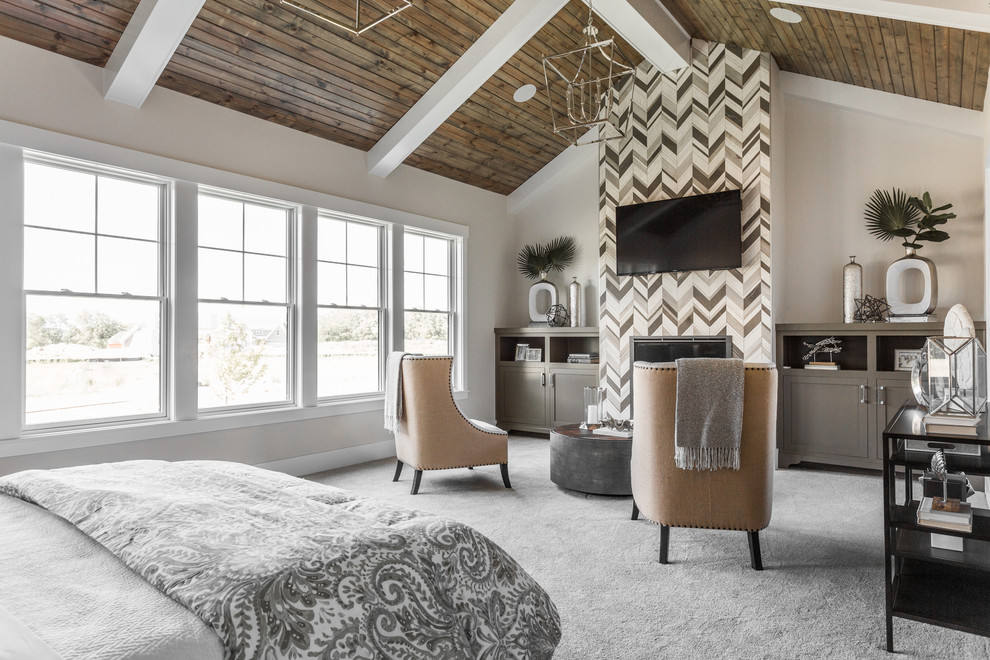Photo of a large transitional master bedroom in Indianapolis with beige walls, carpet, a standard fireplace, a tile fireplace surround and grey floor.