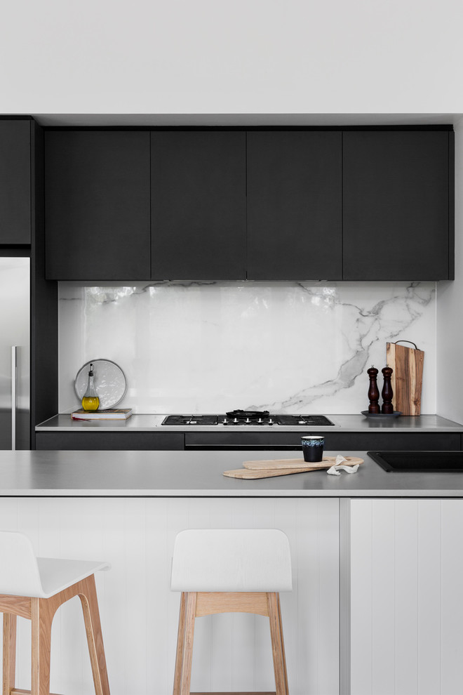 Contemporary galley open plan kitchen in Melbourne with an integrated sink, flat-panel cabinets, black cabinets, concrete benchtops, white splashback, marble splashback, stainless steel appliances, medium hardwood floors and a peninsula.