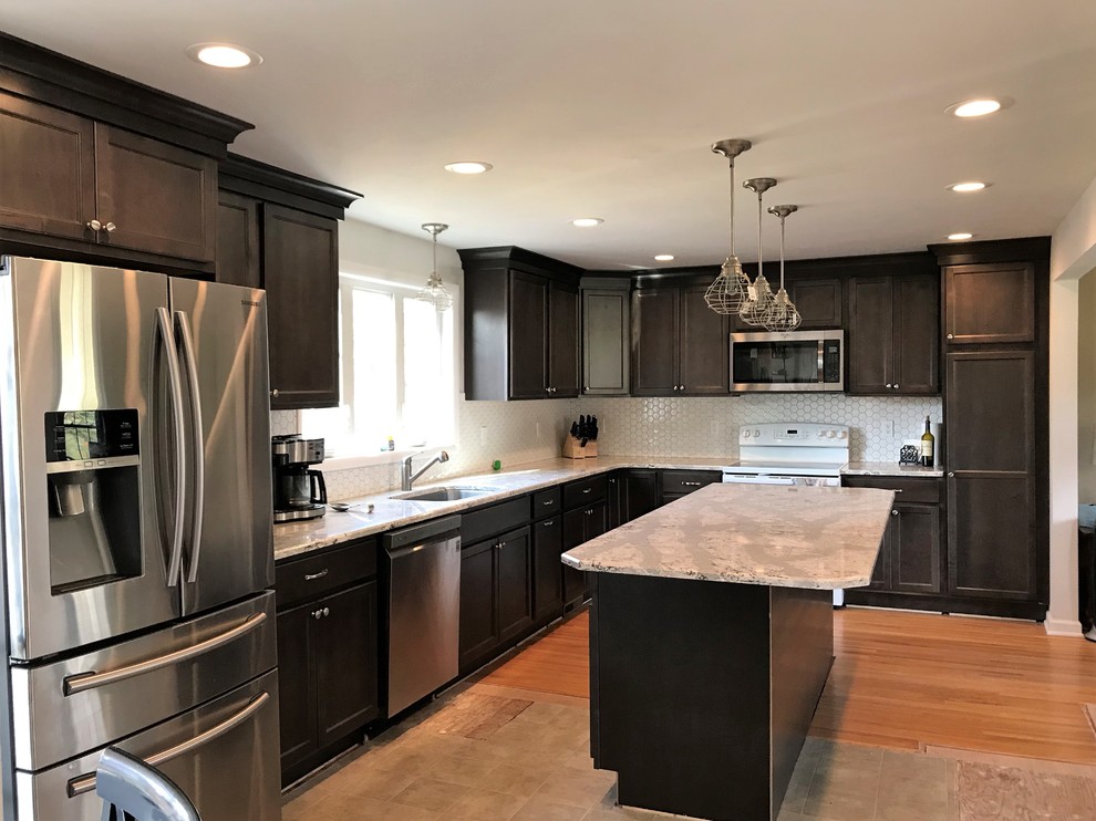 Example of a mid-sized transitional l-shaped eat-in kitchen design in New York with a single-bowl sink, recessed-panel cabinets, dark wood cabinets, quartz countertops, white backsplash, ceramic backsplash, stainless steel appliances and an island
