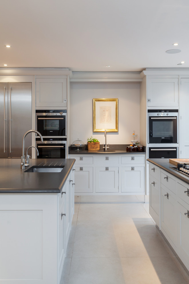 Photo of a transitional kitchen in London with an undermount sink, shaker cabinets, white cabinets and black splashback.