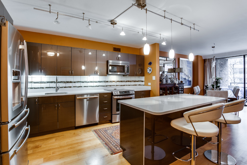 This is an example of a mid-sized contemporary l-shaped kitchen in DC Metro with an undermount sink, quartz benchtops, stainless steel appliances, medium hardwood floors and with island.