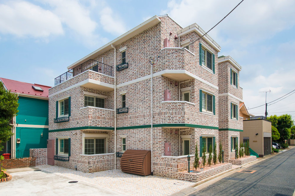 Photo of a large traditional three-storey brick pink apartment exterior in Tokyo.