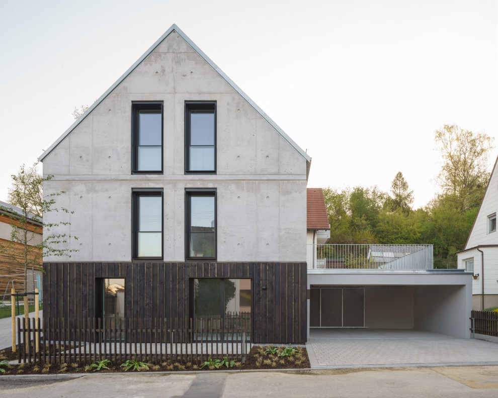Design ideas for an industrial three-storey concrete grey house exterior in Munich with a gable roof and a metal roof.
