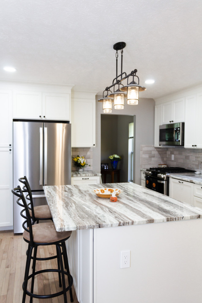 Kitchen - transitional l-shaped light wood floor and beige floor kitchen idea in Columbus with an undermount sink, white cabinets, gray backsplash, an island and gray countertops
