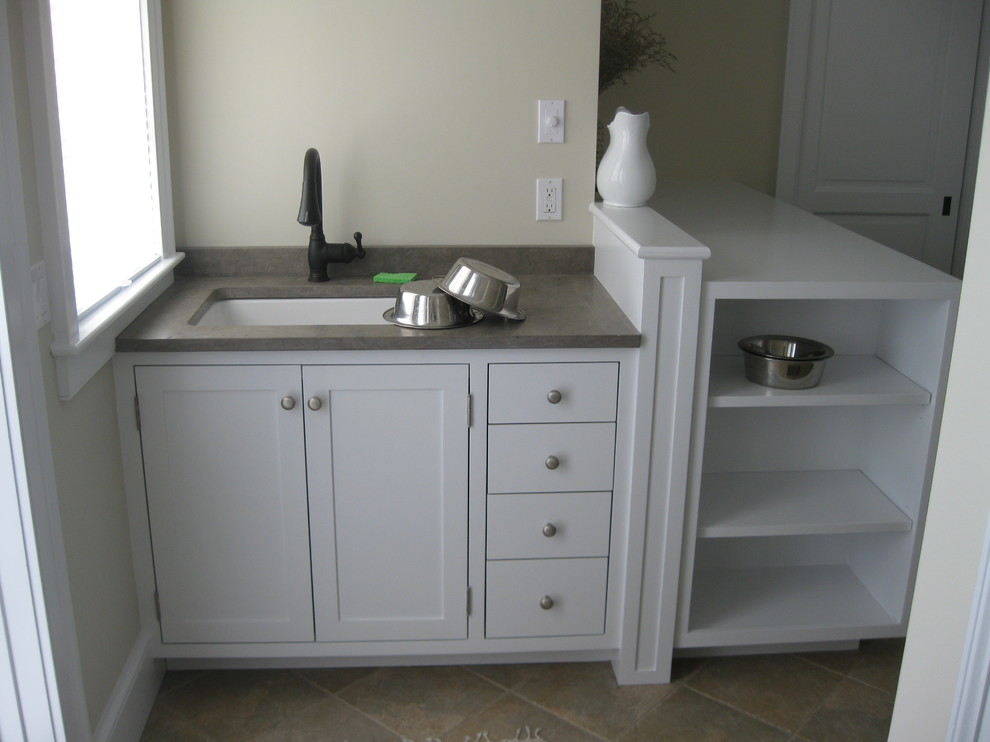 This is an example of a mid-sized transitional l-shaped utility room in Providence with an undermount sink, shaker cabinets, white cabinets, granite benchtops, beige walls, travertine floors and a side-by-side washer and dryer.