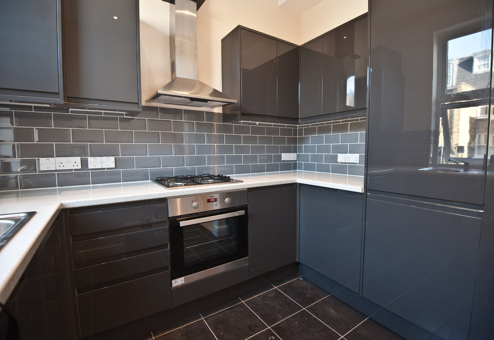 Design ideas for a large modern u-shaped separate kitchen in London with a drop-in sink, flat-panel cabinets, black cabinets, quartz benchtops, grey splashback, ceramic splashback, stainless steel appliances, ceramic floors and no island.