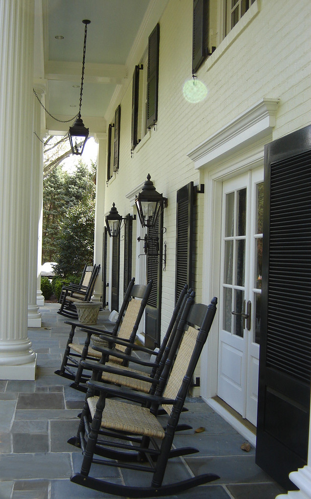 Inspiration for a traditional front yard verandah in DC Metro with natural stone pavers and a roof extension.