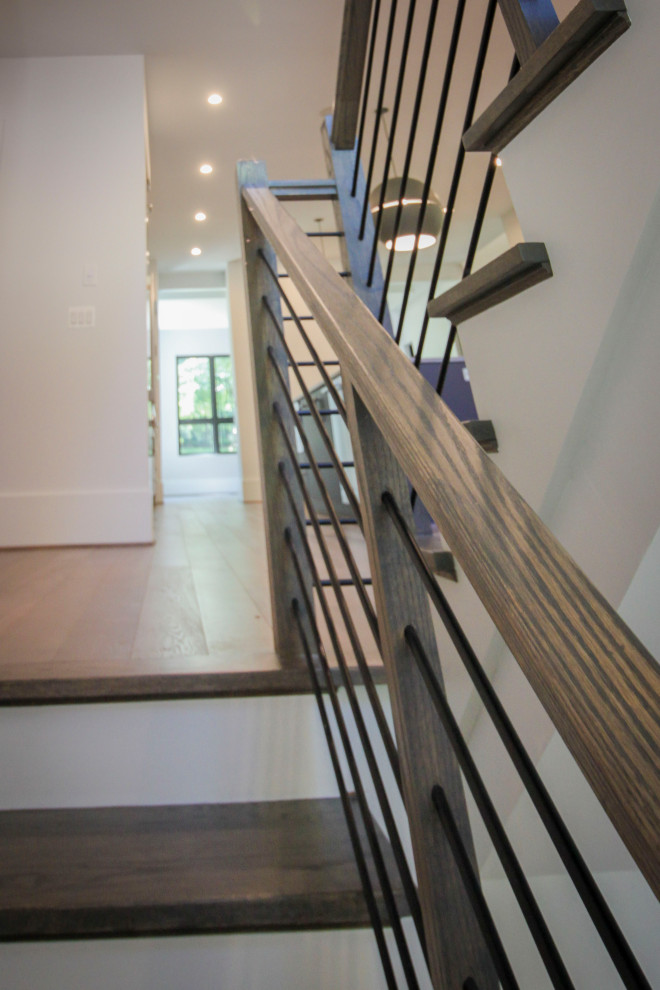 Mid-sized transitional wood u-shaped staircase in DC Metro with wood risers, metal railing and panelled walls.