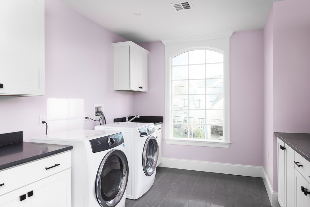 Large traditional galley dedicated laundry room in Boston with an undermount sink, shaker cabinets, white cabinets, quartz benchtops, purple walls, ceramic floors, a side-by-side washer and dryer, grey floor and black benchtop.