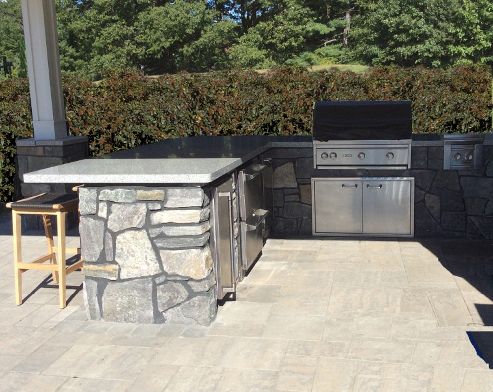 Inspiration for a mid-sized traditional backyard patio in Portland Maine with an outdoor kitchen, natural stone pavers and a roof extension.
