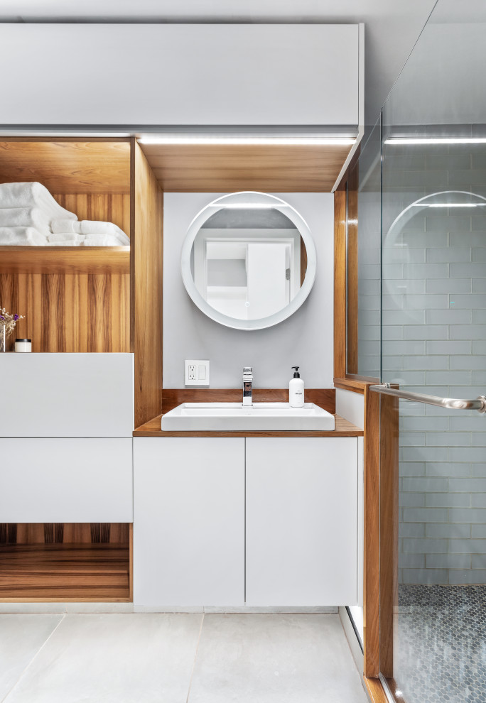 Design ideas for a mid-sized contemporary 3/4 bathroom in Chicago with flat-panel cabinets, white cabinets, blue tile, glass tile, grey walls, cement tiles, wood benchtops, grey floor, a single vanity and a floating vanity.