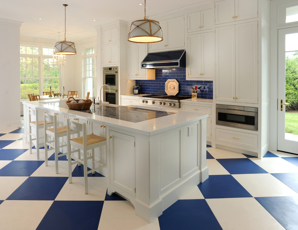 Inspiration for a large traditional single-wall eat-in kitchen in New York with a farmhouse sink, shaker cabinets, white cabinets, blue splashback, subway tile splashback, stainless steel appliances, with island, solid surface benchtops, porcelain floors and multi-coloured floor.