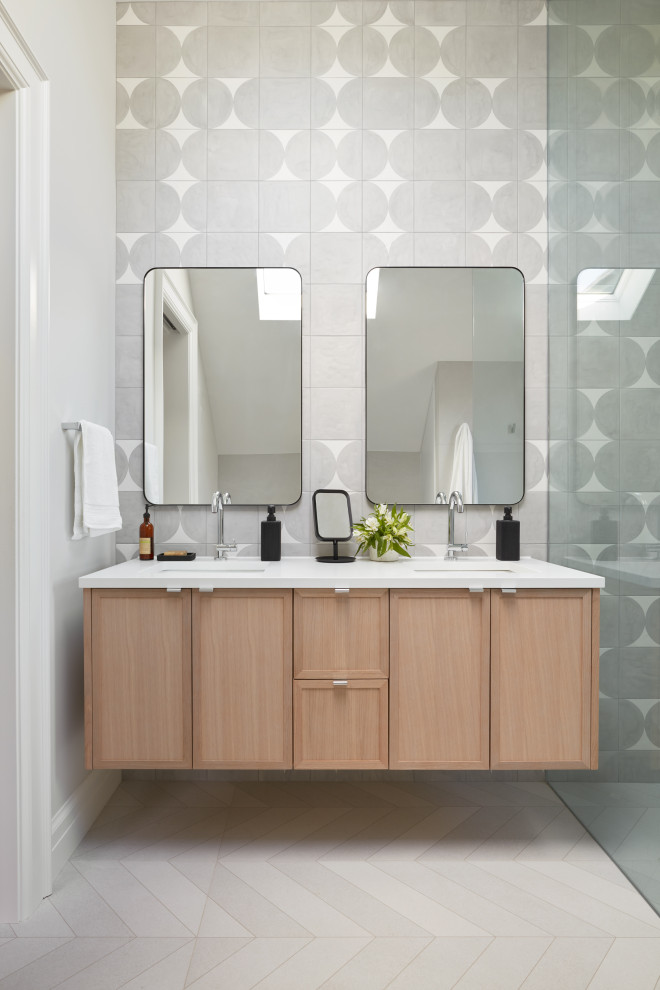 This is an example of a mid-sized modern kids bathroom in Toronto with flat-panel cabinets, light wood cabinets, a freestanding tub, a curbless shower, a wall-mount toilet, white tile, porcelain tile, white walls, porcelain floors, a drop-in sink, engineered quartz benchtops, grey floor, an open shower, white benchtops, a niche, a double vanity and a floating vanity.