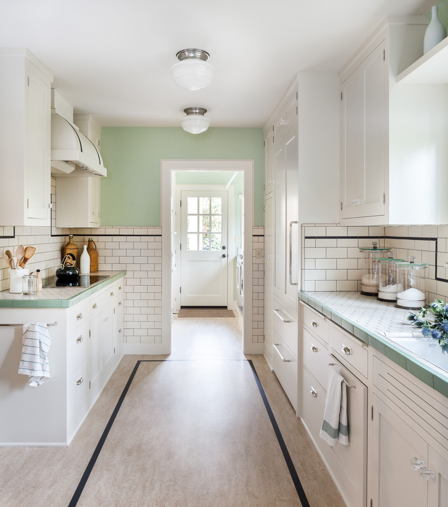 This is an example of a traditional galley kitchen in Sacramento with white cabinets, tile benchtops, white splashback, subway tile splashback, panelled appliances and shaker cabinets.