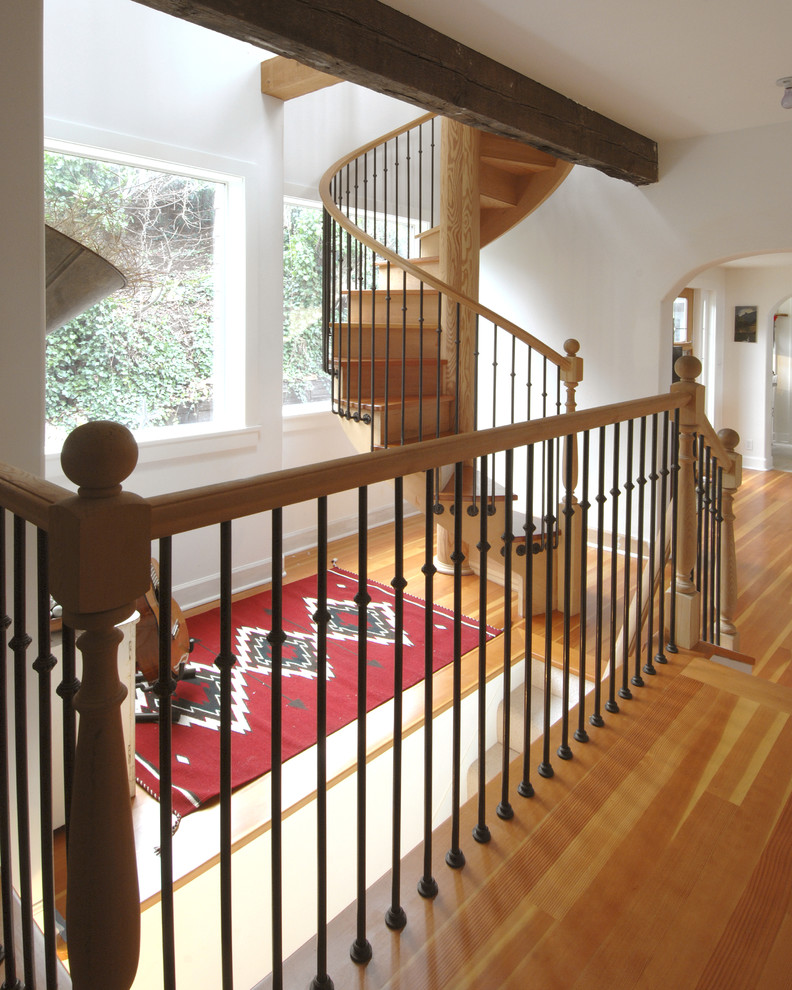 Photo of a large traditional wood spiral staircase in Seattle with wood risers.