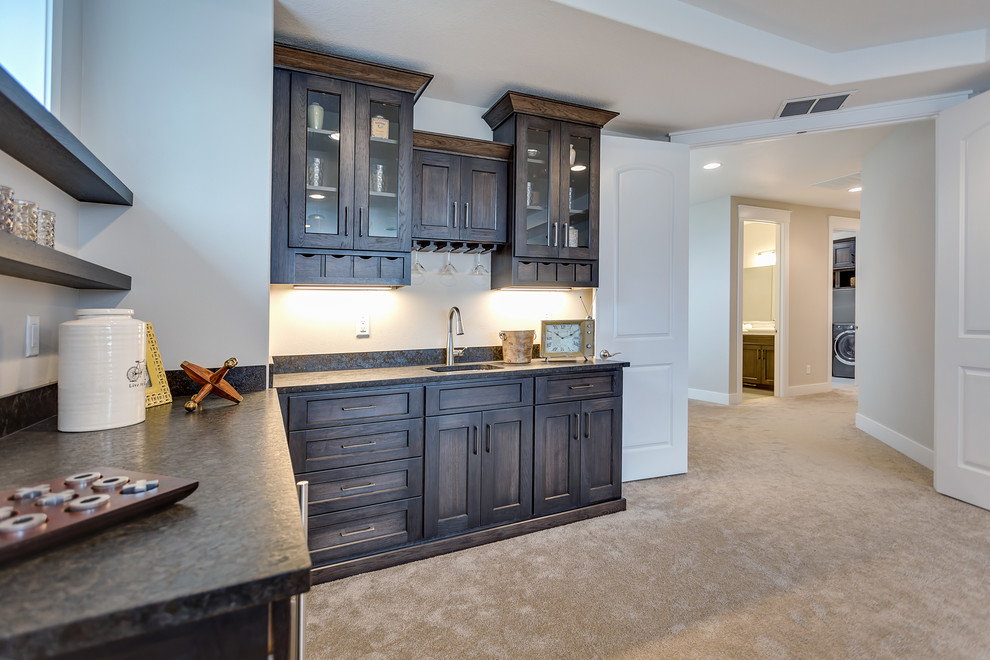 This is an example of an expansive transitional l-shaped wet bar in Portland with carpet, an undermount sink, recessed-panel cabinets, dark wood cabinets, granite benchtops, multi-coloured splashback and stone slab splashback.