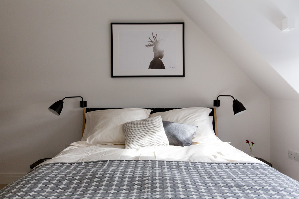 This is an example of a mid-sized contemporary master bedroom in London with white walls and light hardwood floors.