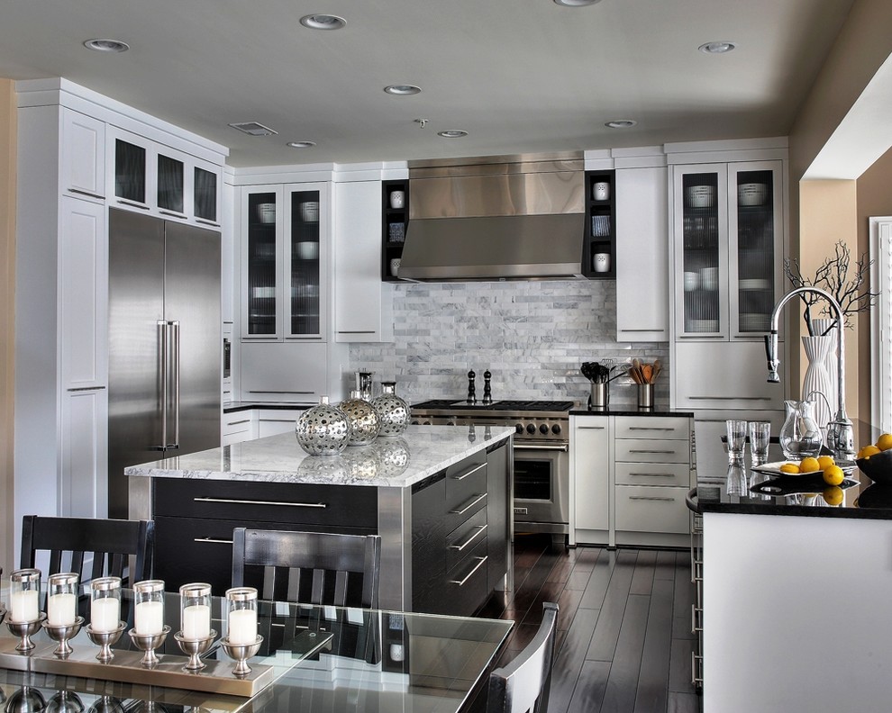 This is an example of a large contemporary u-shaped eat-in kitchen in DC Metro with glass-front cabinets, stainless steel appliances, granite benchtops, white splashback, stone tile splashback, dark hardwood floors, with island, an undermount sink, white cabinets and brown floor.