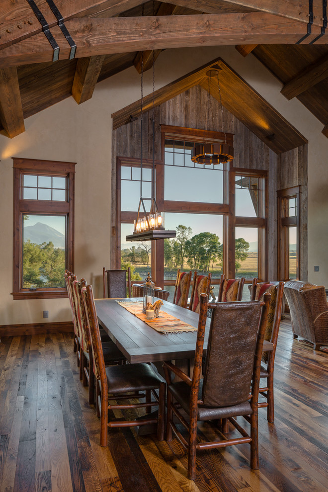 Inspiration for a country dining room in Other with multi-coloured walls, medium hardwood floors, a wood stove, a wood fireplace surround and multi-coloured floor.