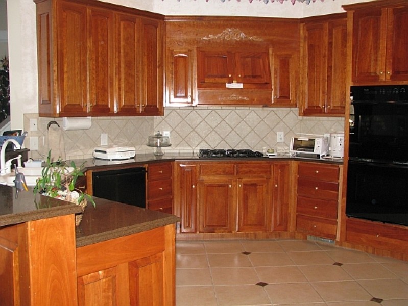 U-shaped ceramic tile open concept kitchen photo with raised-panel cabinets, medium tone wood cabinets, beige backsplash, black appliances and no island