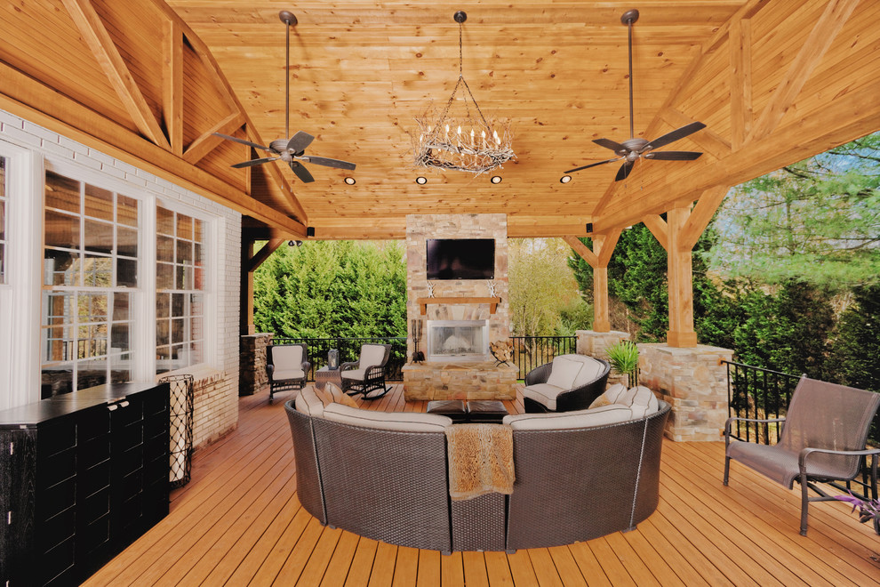 Design ideas for an expansive arts and crafts backyard deck in Raleigh with a fire feature and a roof extension.