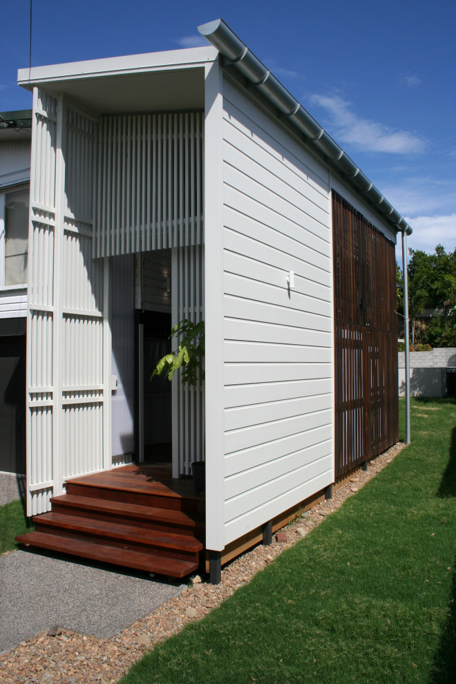 Ejemplo de entrada moderna de tamaño medio con paredes blancas, suelo de madera en tonos medios, puerta corredera, puerta blanca, suelo marrón y boiserie
