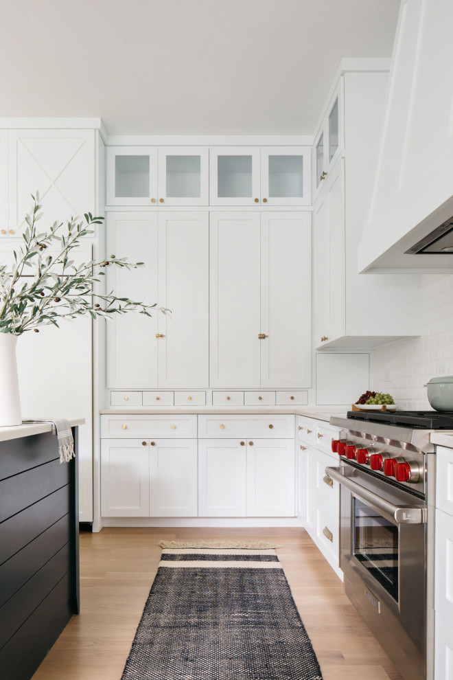 Esempio di una grande cucina moderna con ante in stile shaker, ante bianche, paraspruzzi bianco, elettrodomestici in acciaio inossidabile, pavimento in legno massello medio e top beige
