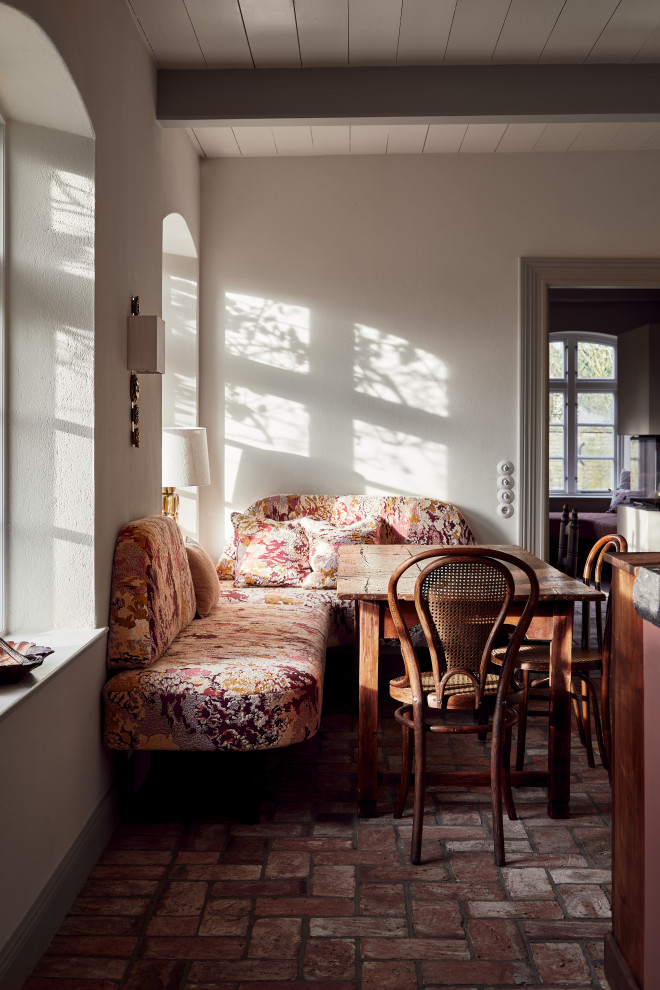 На фото: маленькая гостиная-столовая в стиле фьюжн с белыми стенами, кирпичным полом, красным полом и балками на потолке для на участке и в саду с
