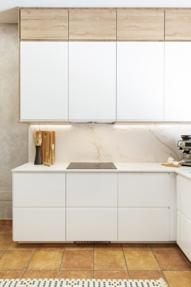 Inredning av ett modernt mellanstort vit vitt u-kök, med en undermonterad diskho, släta luckor, vita skåp, bänkskiva i kvarts, vitt stänkskydd, integrerade vitvaror, terrazzogolv och rött golv
