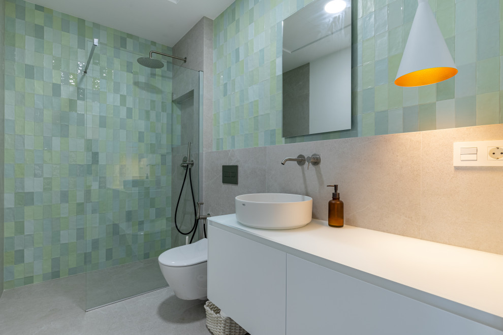 Exemple d'un WC et toilettes scandinave de taille moyenne avec un placard avec porte à panneau encastré, WC à poser, un carrelage vert, des carreaux de céramique, un mur gris, un sol en carrelage de céramique, un plan de toilette en bois, un sol gris, un plan de toilette blanc et meuble-lavabo suspendu.